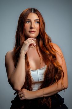 Stunning portrait of a red-haired woman with a thoughtful pose and elegant style.