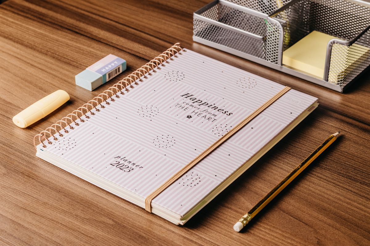 Planner mensal com caneta e pequenos objetos de trabalho para organizar prioridades de outubro