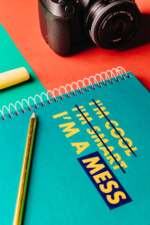 Pencil Lying on a Green Note Pad with a Camera in the Background