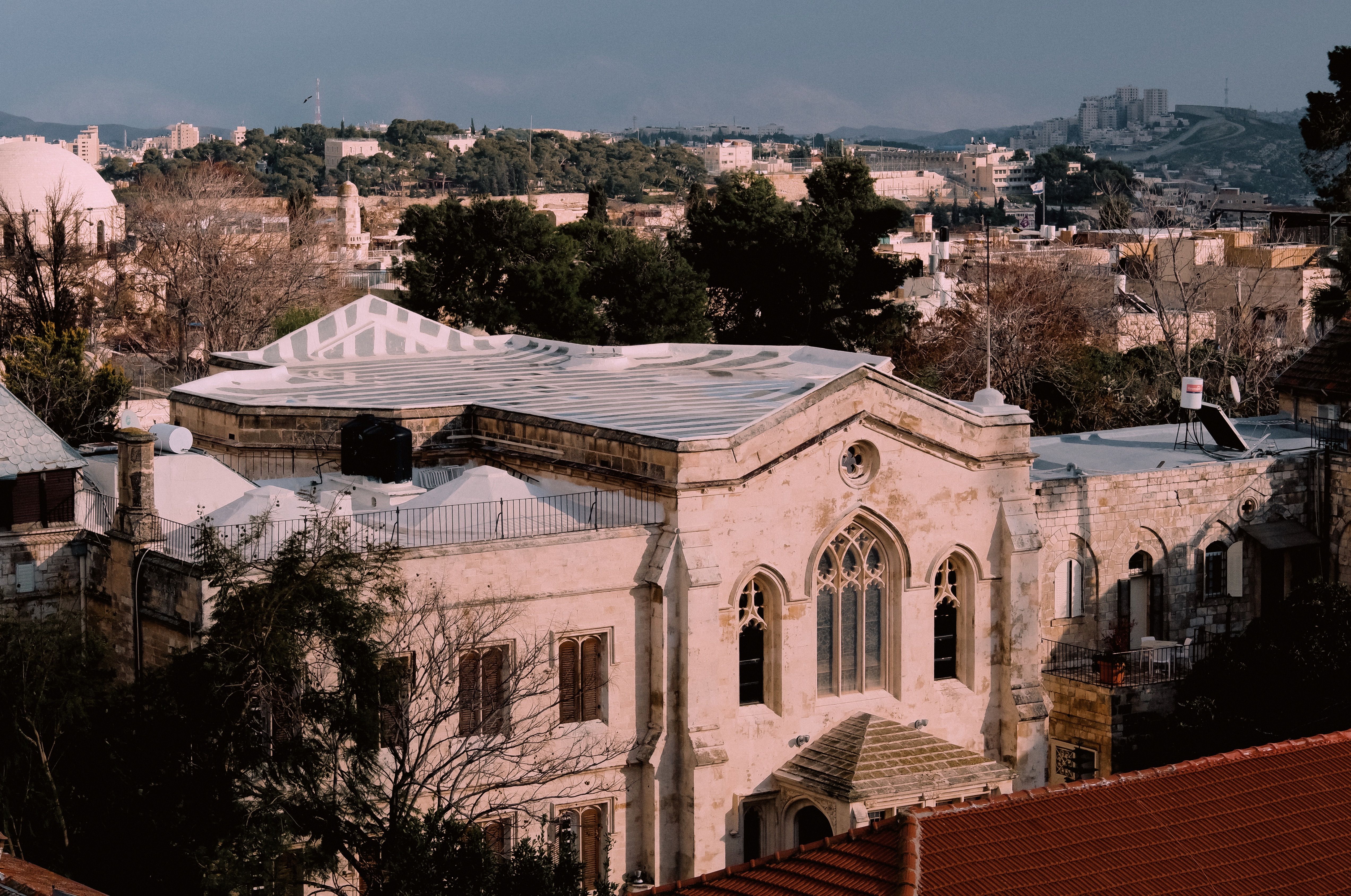 Elegant stone church surrounded by a cityscape under a soft evening sky.