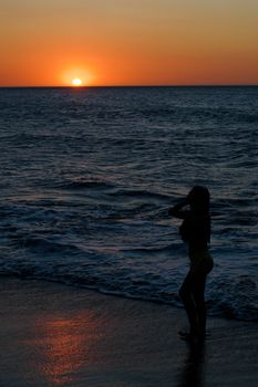 A silhouetted woman stands by the ocean at sunset in Santa Marta, Colombia.