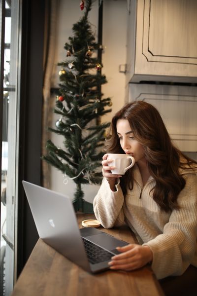 Woman with coffee beside a window, photo by Melike B on Pexels
