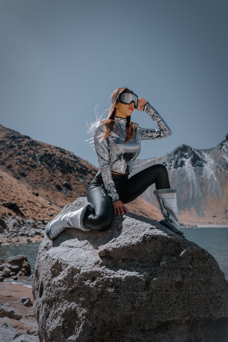 Fashion Model Sitting On Rock In Mountains Landscape