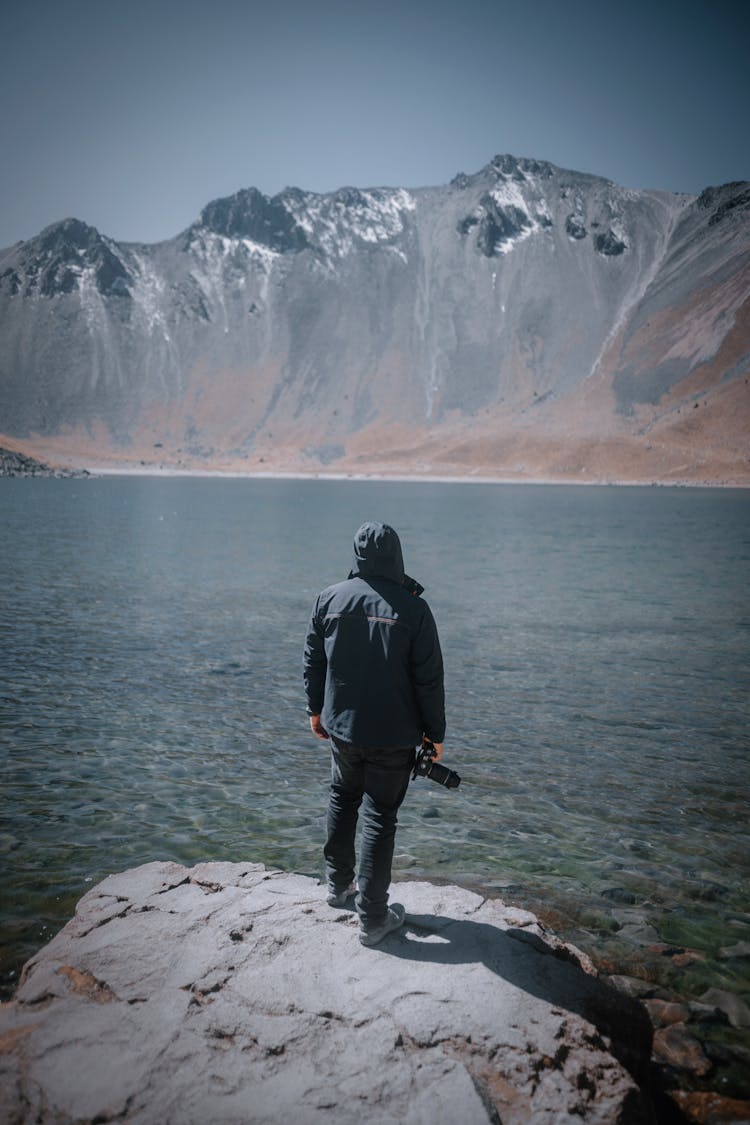 Man With Camera Standing On Rock In Mountains Landscape