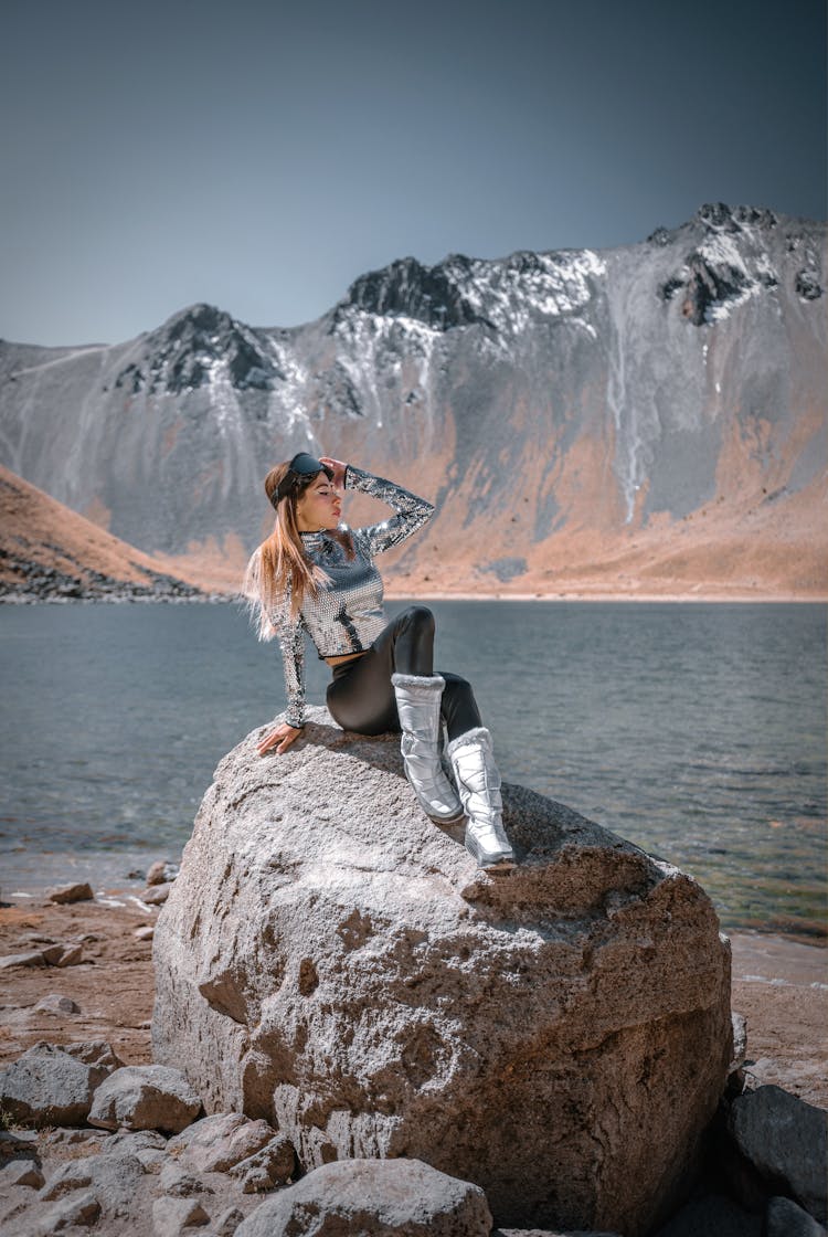 Fashion Model Sitting On Rock In Mountains Landscape