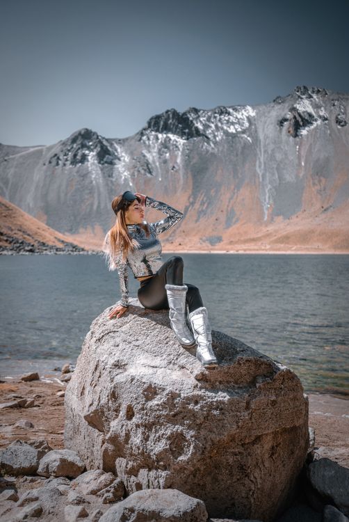 Fashion Model Sitting on Rock in Mountains Landscape · Free Stock Photo