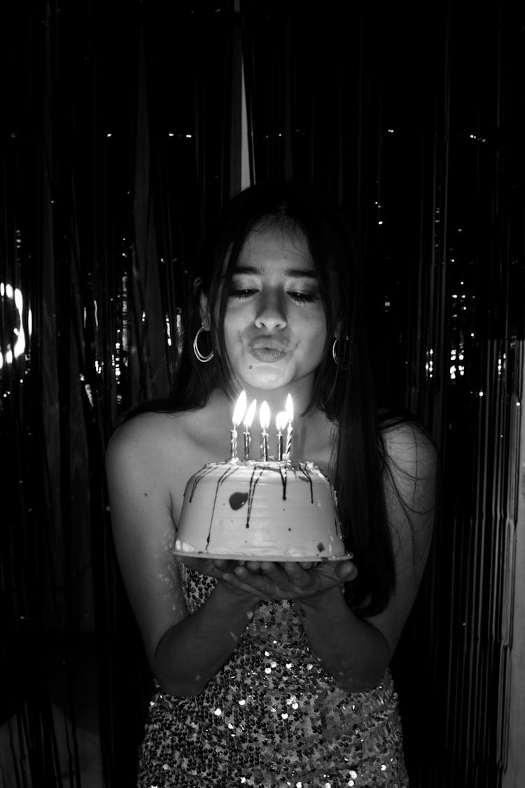 Grayscale Photo Of A Woman Blowing A Cake 