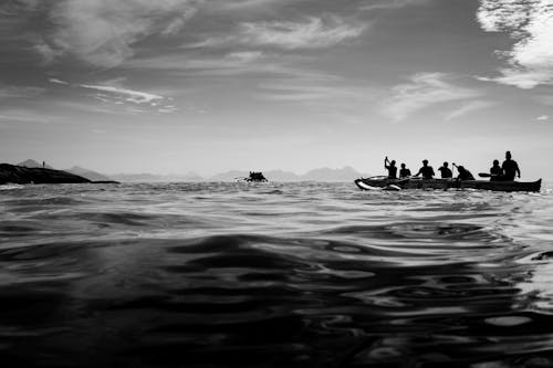 People on Boat on Sea Coast in Black and White