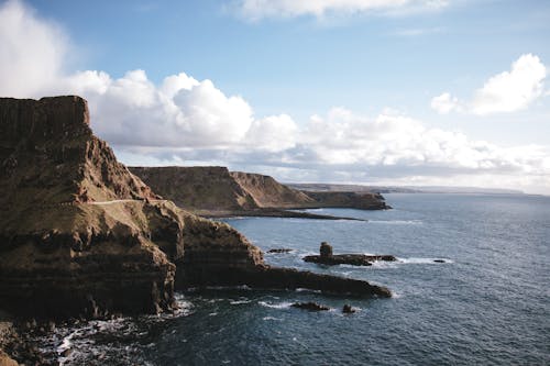 Rocky coast against calm sea during sunny day