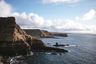 Rocky coast against calm sea during sunny day