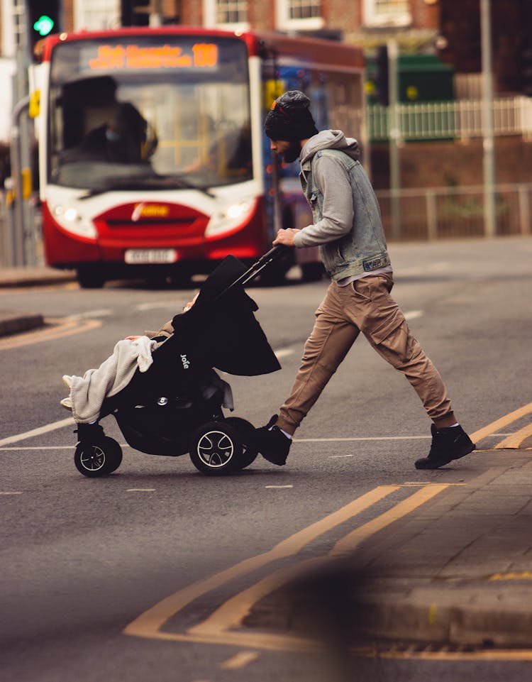 A Man Pushing A Stroller While Crossing The Street