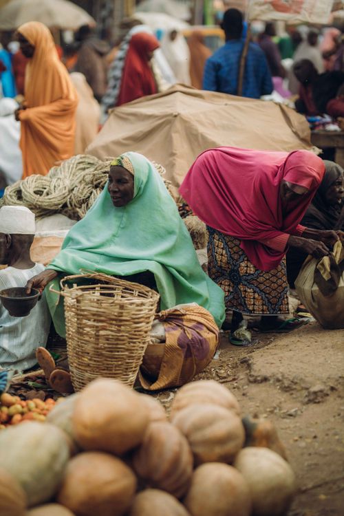 Free Colorful street market scene with people trading fresh vegetables and goods outdoors. Stock Photo