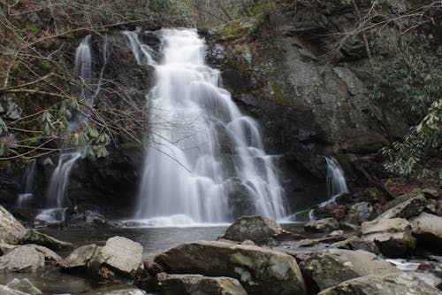 Free Tranquil waterfall cascading over rocks in Sevierville, TN's lush forest setting. Stock Photo