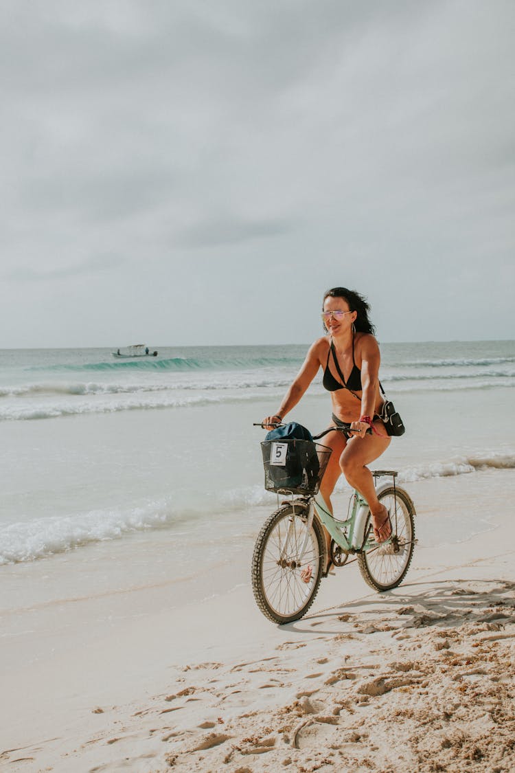 A Woman Riding A Bike At The Beach 