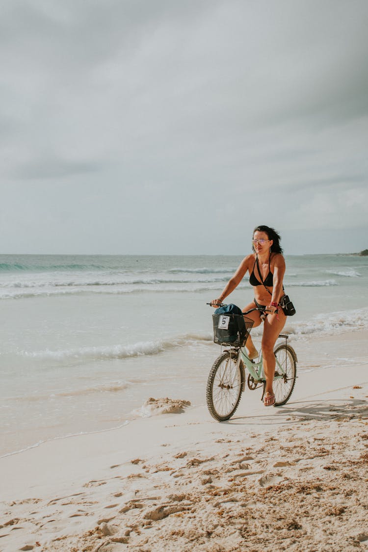 A Woman Riding A Bike At The Beach