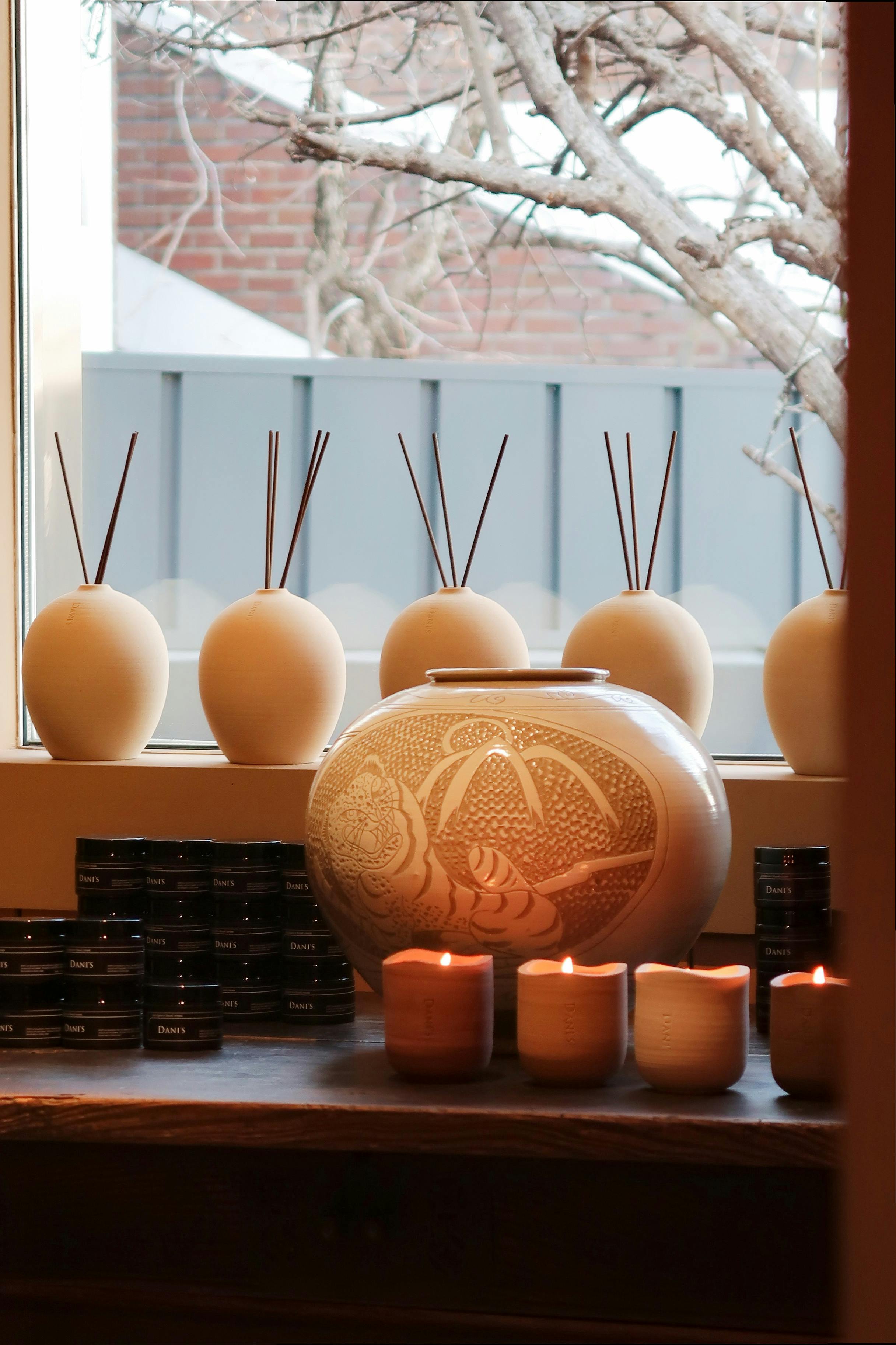 A serene indoor display of aromatherapy candles and diffusers on a wooden table by a window.