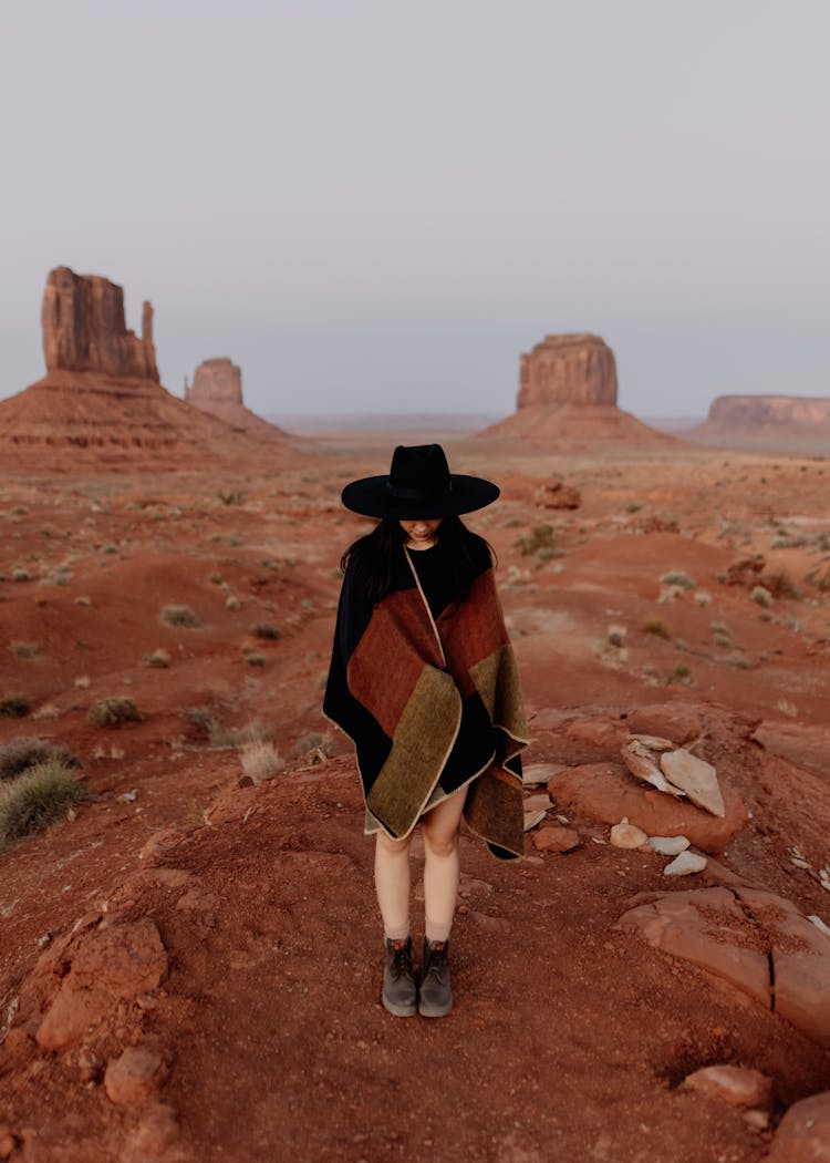 Woman In Hat Standing In Desert Landscape