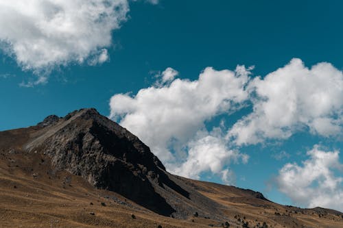 View of a Rocky Mountain Peak under Blue Sky with White Clouds 