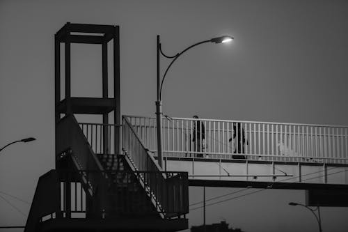 Grayscale Photo of People Walking on a Bridge