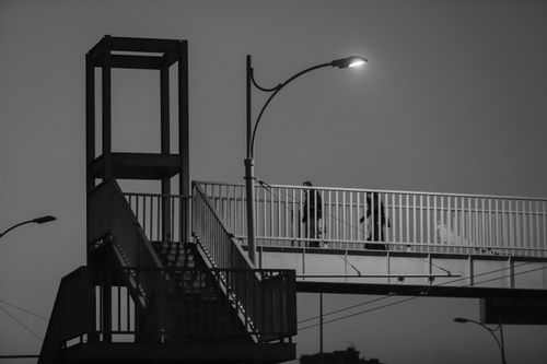 Free Black and white photo of people walking on an urban footbridge under streetlights. Stock Photo