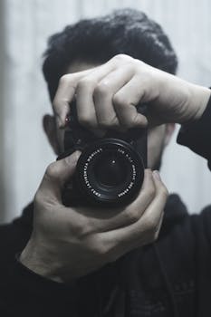 Capturing a moment with a close-up of a camera lens held in hands, reflecting the art of photography.