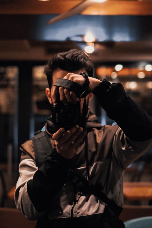 Free Photographer taking a picture indoors at night, showcasing urban photography. Stock Photo