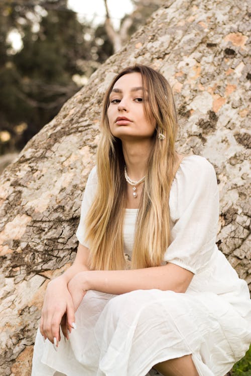 Young Blonde in a White Dress Posing Outdoors 