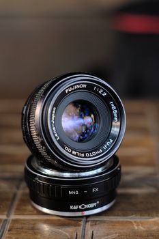 A detailed shot of a vintage Fujinon camera lens with adapter ring.
