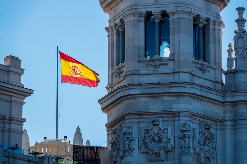 Bandera de España ondeando junto a la arquitectura histórica en Madrid.