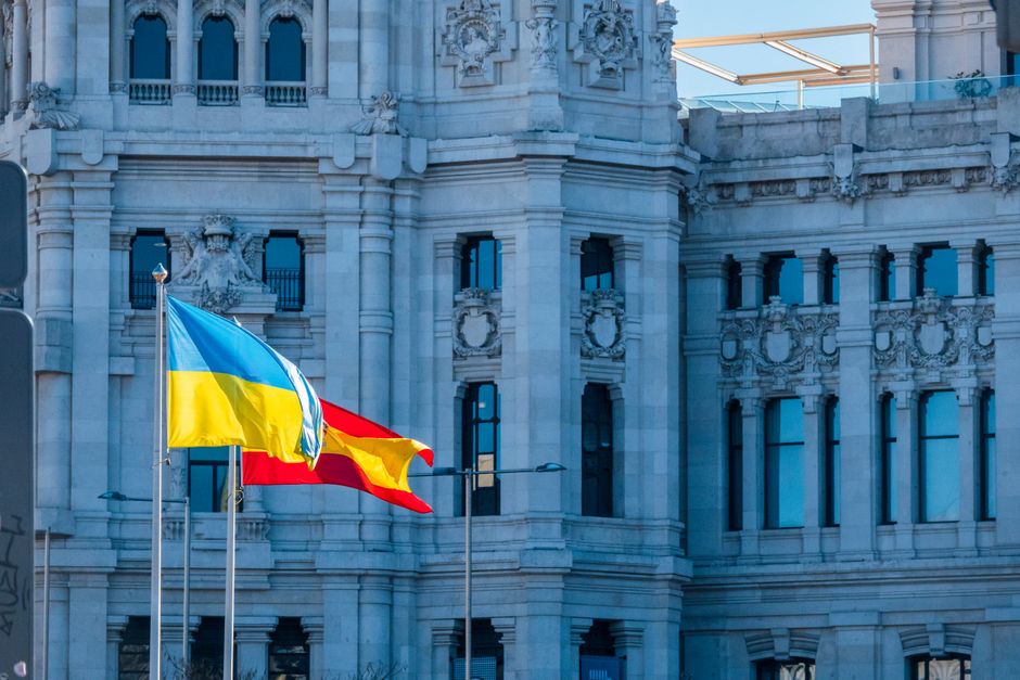 Spanish and Ukrainian flags flying outside a historic building in Madrid, Spain.