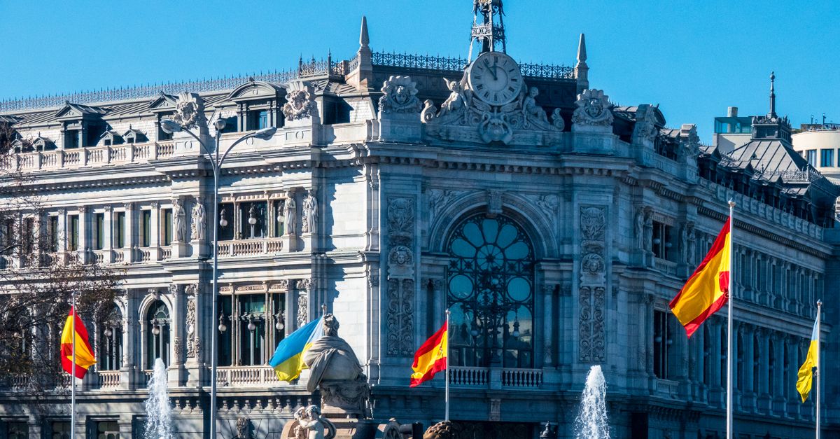 Vista del icónico edificio del Banco de España y de la Fuente de Cibeles, adornados con banderas en Madrid.