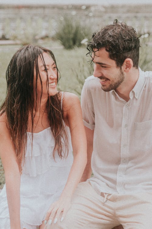 Asian Woman and Man Sitting Next to Each Other and Smiling