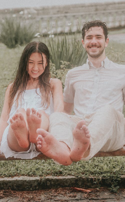 Wet Couple in White Dress Sitting on Grass