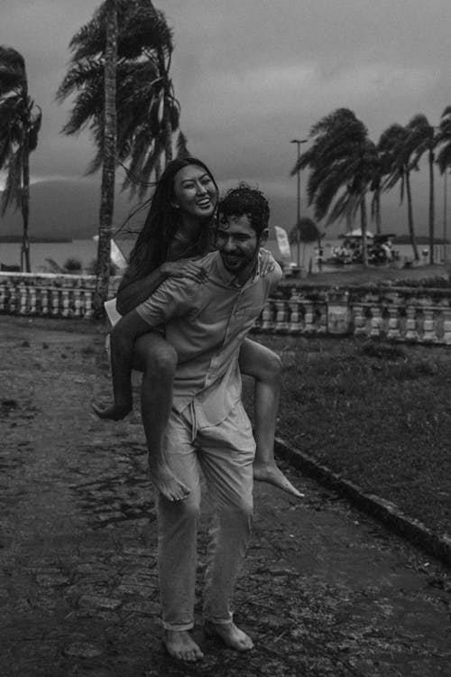 A Grayscale Photo of a Man Carrying His Partner