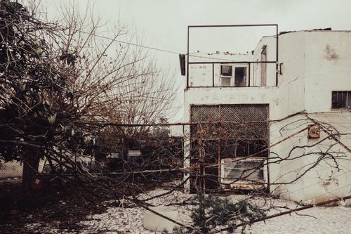 Free An eerie winter scene of an abandoned house with a fallen tree, conveying neglect and decay. Stock Photo