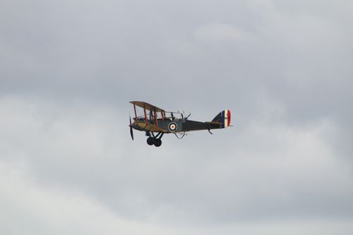 Free Classic military biplane soaring against a cloudy sky, perfect for aviation history themes. Stock Photo