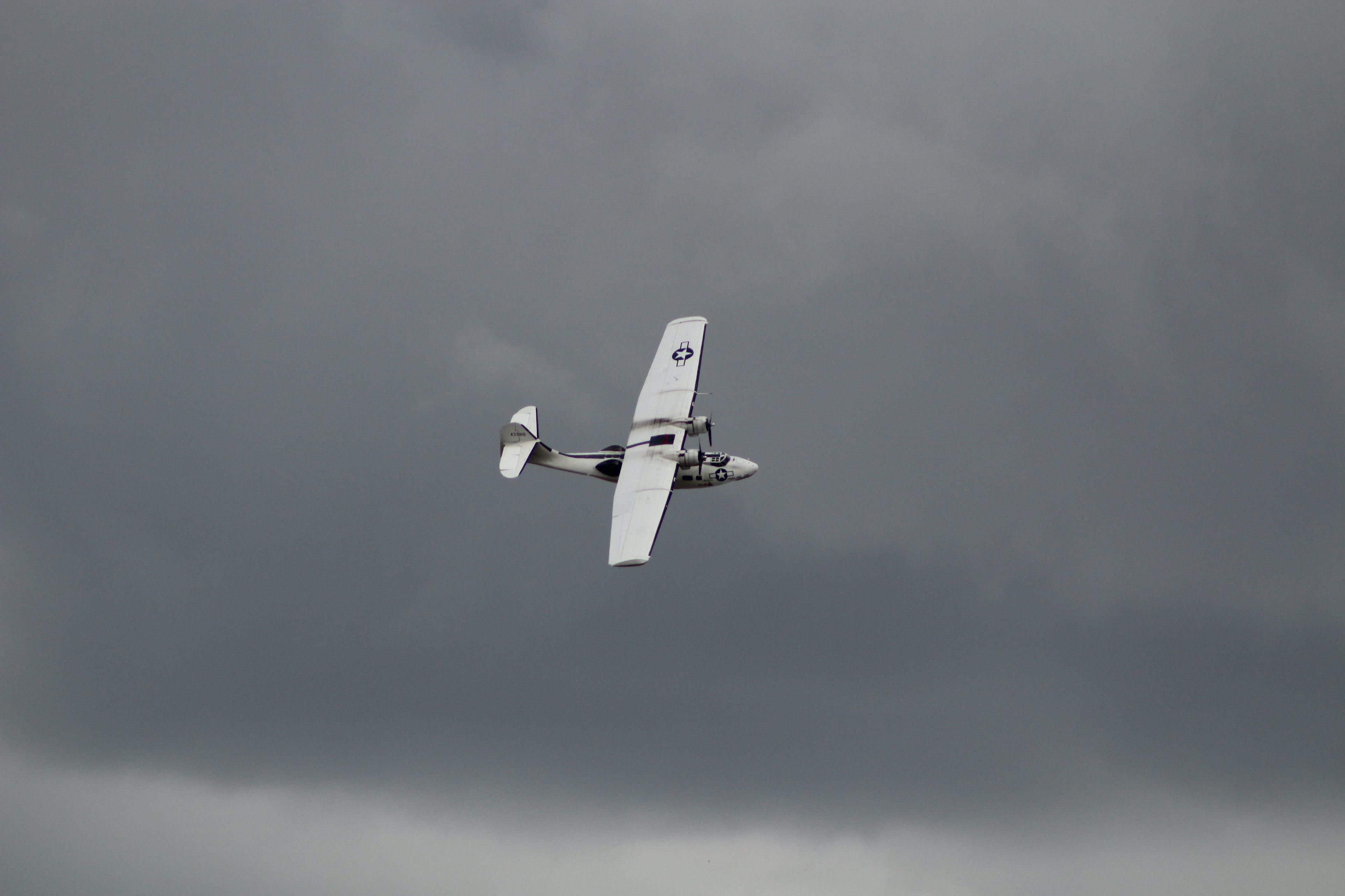 Un avión militar gris volando bajo un cielo nublado