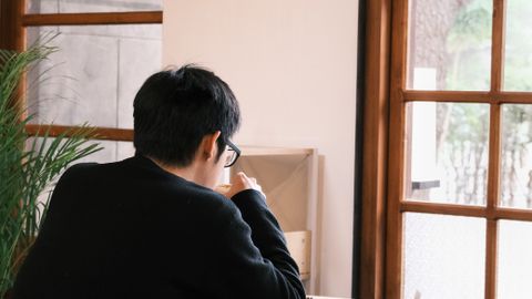 A man in a cafe enjoys solitude by large windows, creating a serene atmosphere.