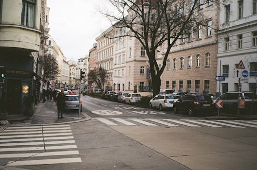Busy city street scene in Europe with pedestrian crossing and parked cars on a winter day.