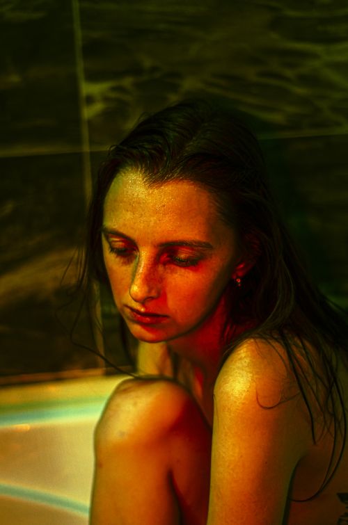 Free Moody portrait of a woman in a bathtub with dramatic lighting. Stock Photo