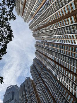 Dramatic upward view of Hong Kong high-rise buildings against a cloudy sky.