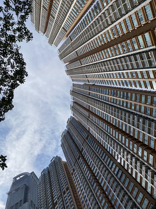 Free Dramatic upward view of Hong Kong high-rise buildings against a cloudy sky. Stock Photo