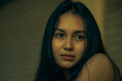 Free Close-up portrait of a young woman with long dark hair and a thoughtful expression. Stock Photo