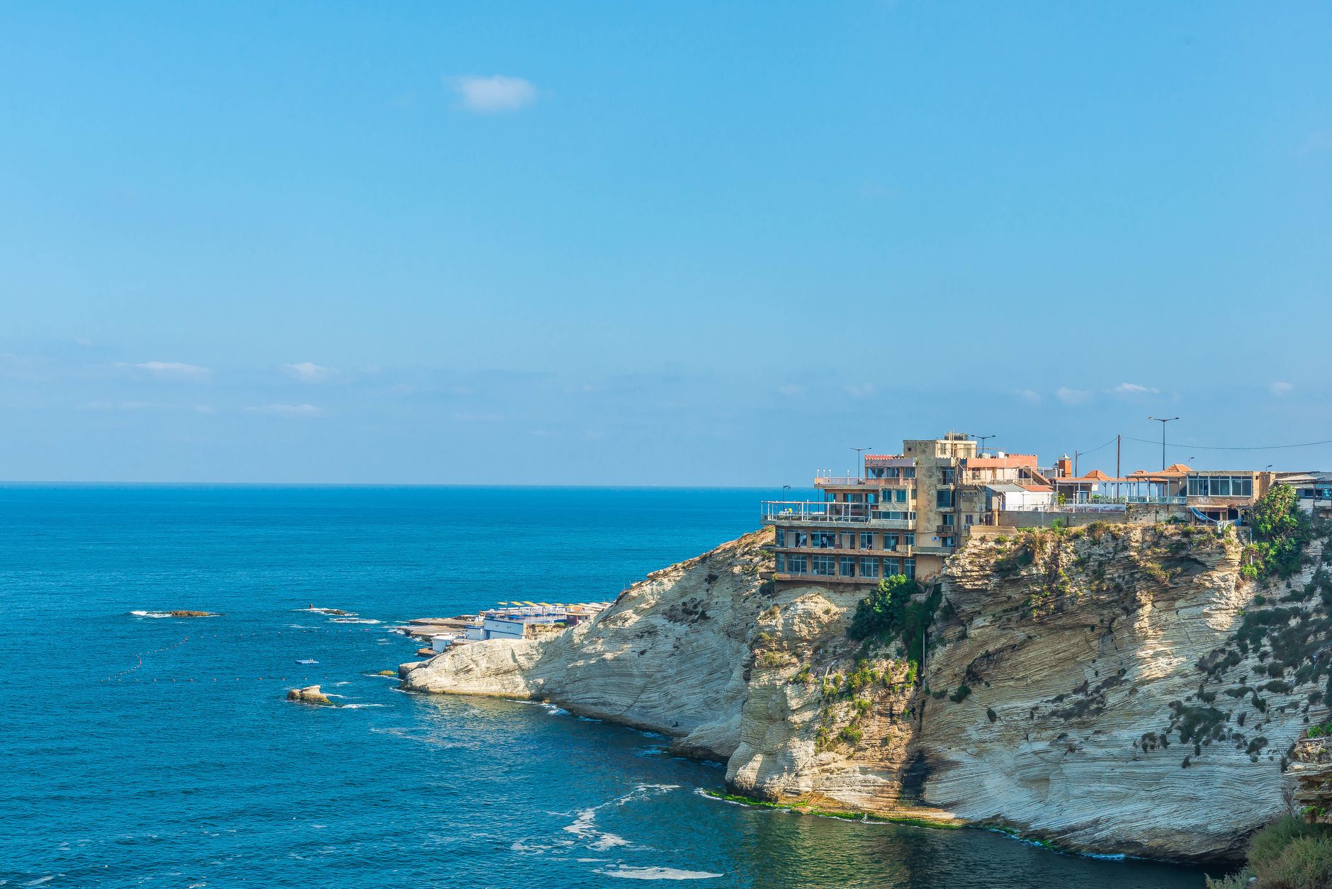 Beautiful seaside cliff with a resort, overlooking the clear blue waters on a sunny day.