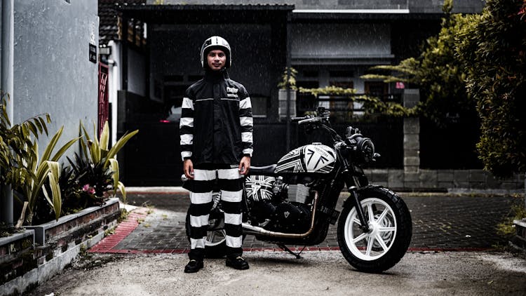 Photo Of A Young Man In A Helmet Standing Next To A Motorcycle