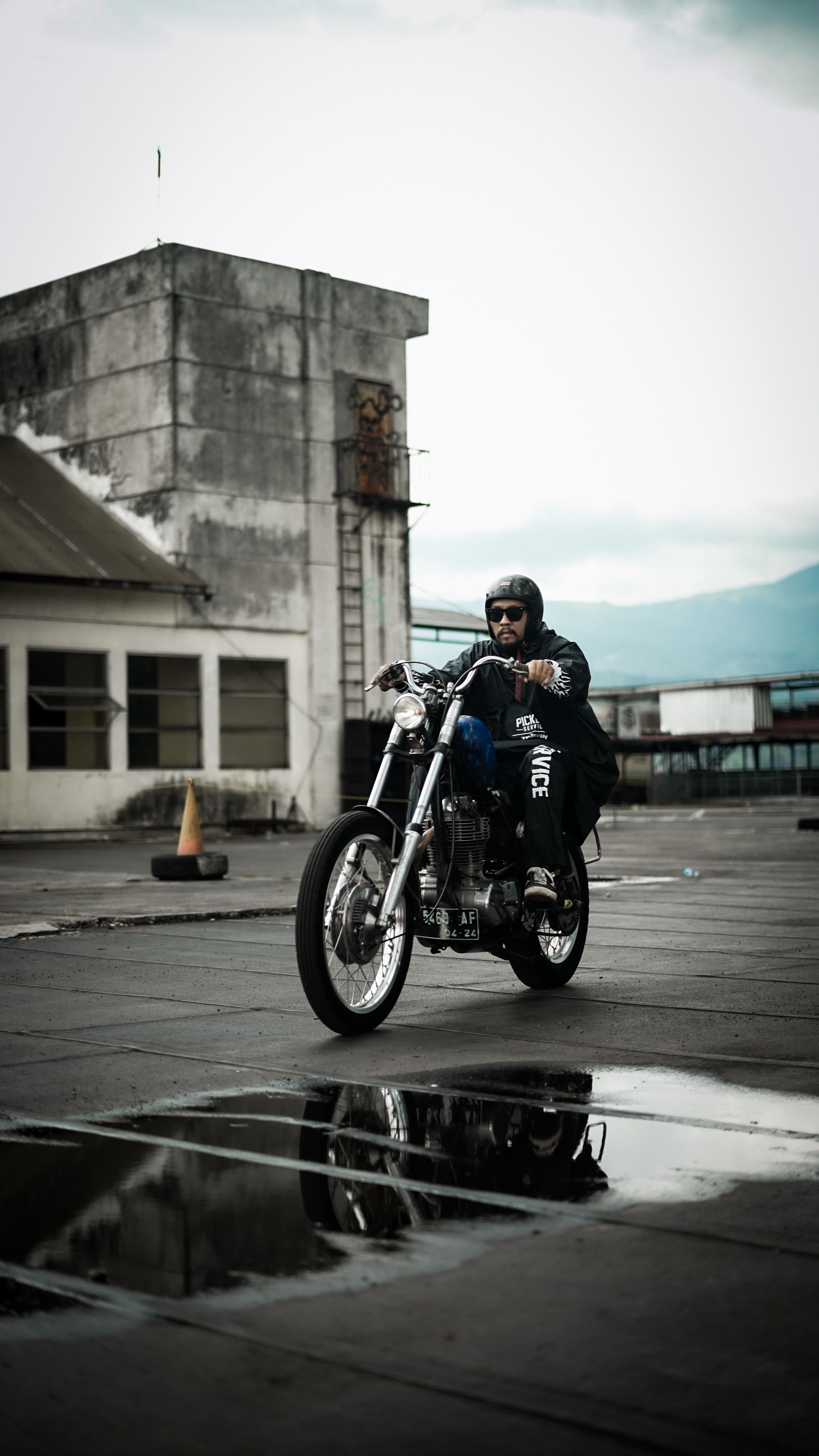 A motorcyclist rides an urban street with reflections on a wet surface, exuding a sense of adventure.