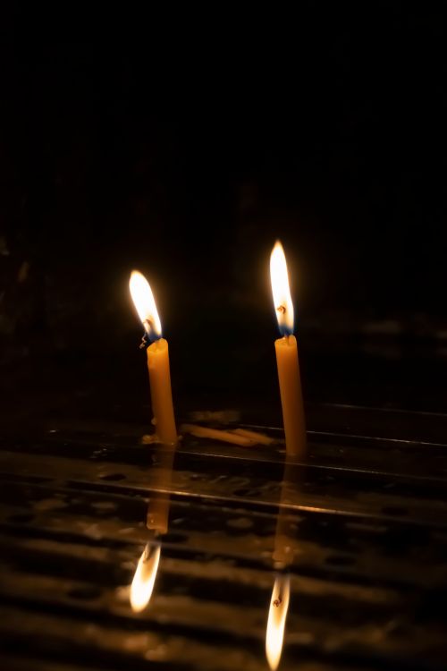 Free Two candles casting a warm glow in the dark, creating a reflective ambiance. Stock Photo