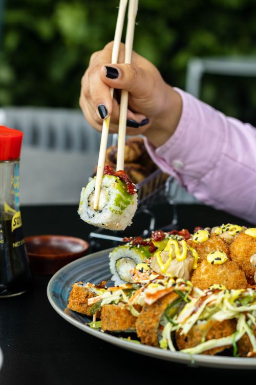 Free Close-up of sushi being held with chopsticks in a restaurant setting. Stock Photo