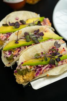 Close-up of gourmet tacos with avocado and microgreens, perfect for food lovers.