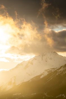 Golden sunset illuminates snowy mountains in Crans-Montana, Switzerland.
